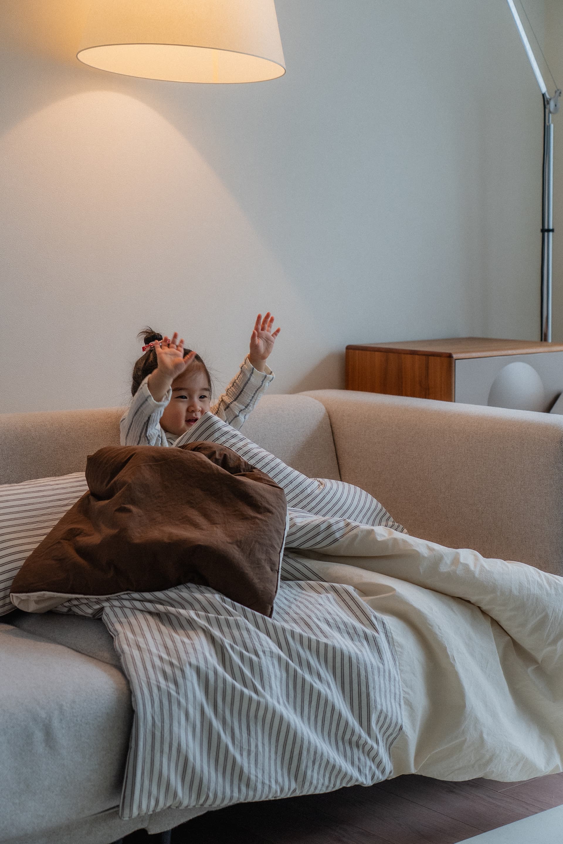 Child sitting on cozy striped bedding